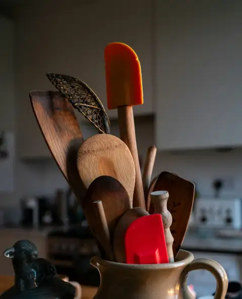Kitchen tools: A cup filled with wooden utensils on top of a table