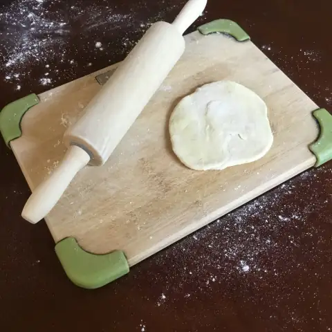 Chakla & belan: white dough on brown wooden chopping board