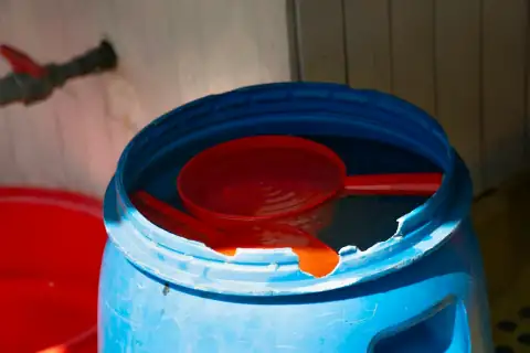 Water drums: a blue bucket with a red spoon inside of it