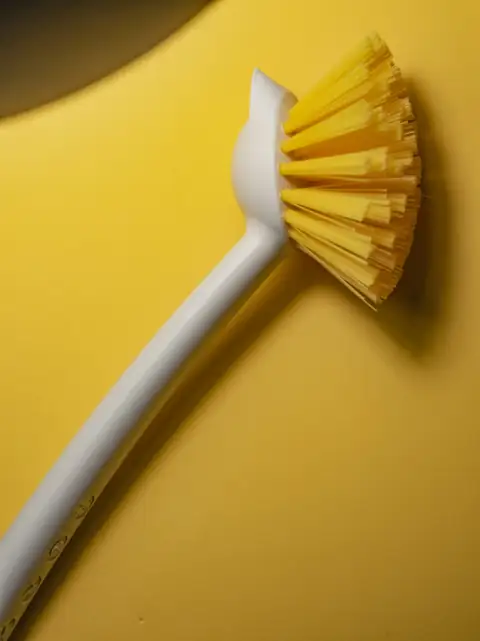 Toilet & basin brushes: A white and yellow scrub brush on a yellow background