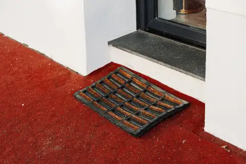 Doormats: A doormat sits on a red floor by a door