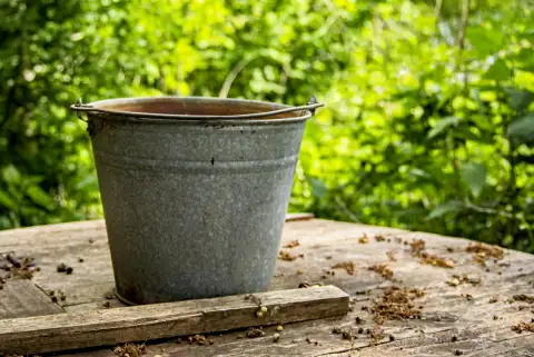Buckets: gray steel bucket on brown wooden table