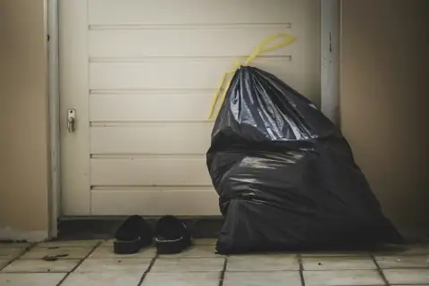 Garbage bags: black plastic bag beside white wall
