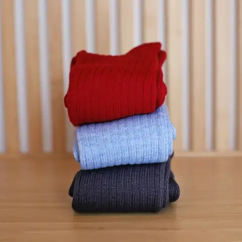 Socks: a stack of three socks sitting on top of a wooden table