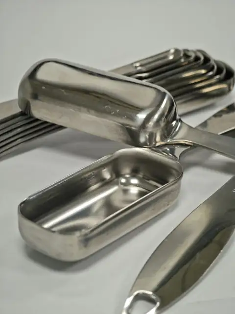 Steel utensils: Stainless steel scoops and measuring spoons on a white surface