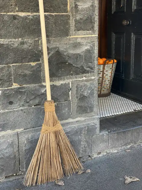 Brooms: brown broom leaning on gray concrete wall