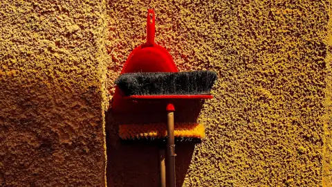 Dustpans: Red dustpan and broom leaning against wall