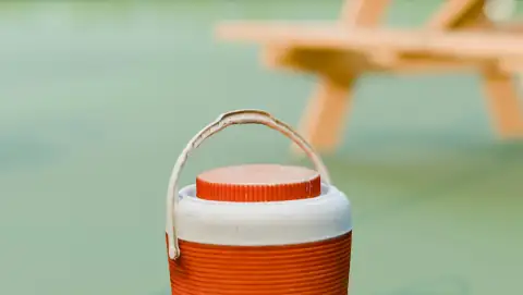Water campers & jugs: An orange and white cooler sits on green ground outdoors