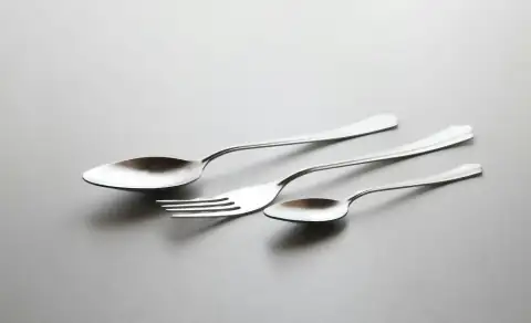 Steel utensils: silver spoon and fork on white table