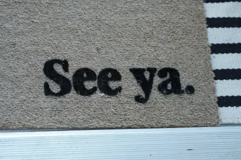 Doormats: A tan coir doormat with black text reading "See ya." beside a striped rug