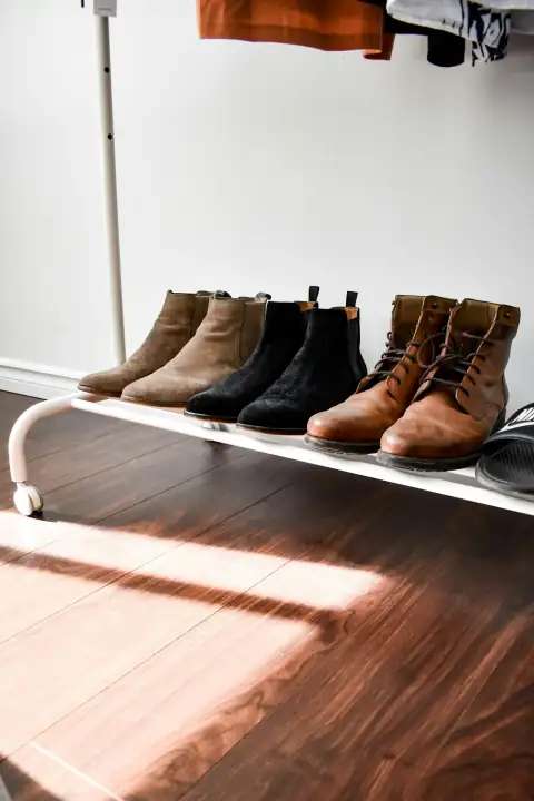 Shoe racks: black and brown leather boots on brown wooden floor