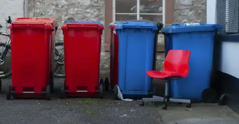 Dustbins: Four colorful trash bins with a red chair