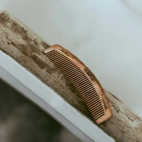 Combs & grooming: brown hair comb on white wooden table