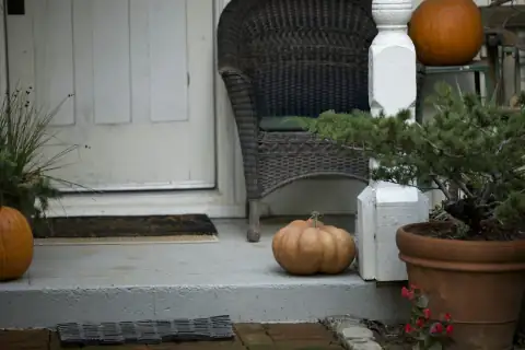 Doormats: Pumpkins decorate a porch with a wicker chair