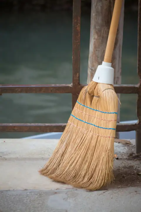 Brooms: a broom sitting on the ground next to a body of water