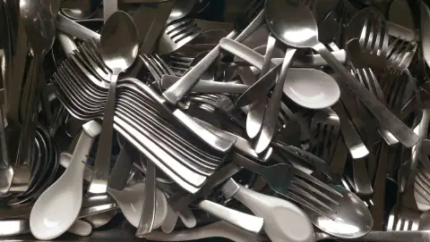Steel utensils: gray and white spoon and fork lot closeup photo