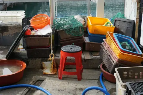 Tubs & tokna: A red plastic stool surrounded by stacks of colorful crates on a dock
