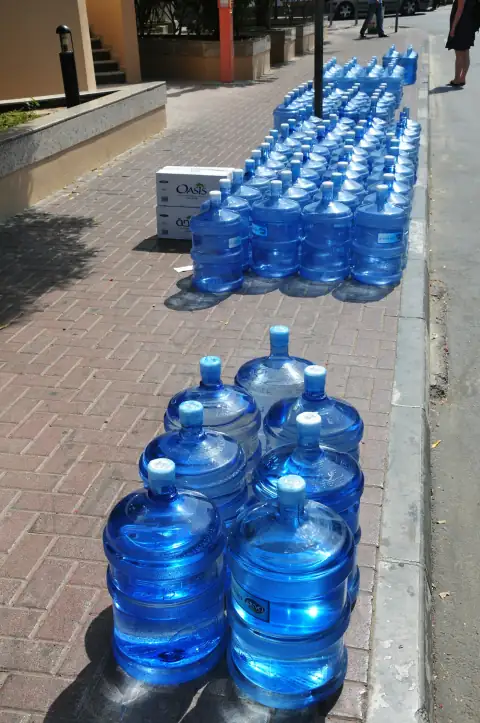 Water campers & jugs: a row of blue water bottles sitting on the side of a road